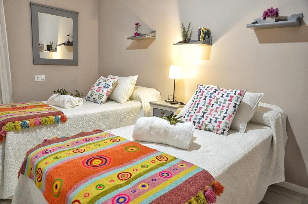 Segundo dormitorio con dos camas, espejo y estanterías