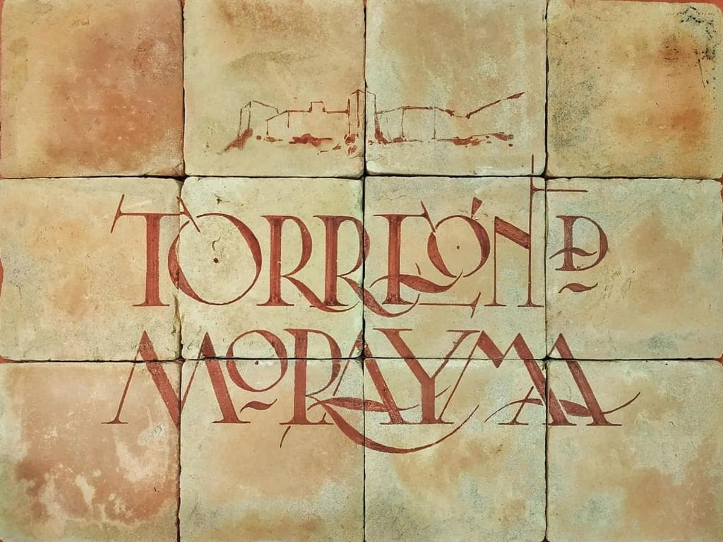 Azulejo pintado a mano con el nombre de la casa y la silueta del castillo de Baena