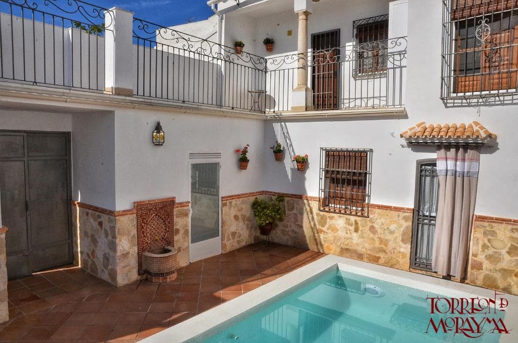 Patio de la casa visto desde el balcón, con la piscina y las macetas en la pared